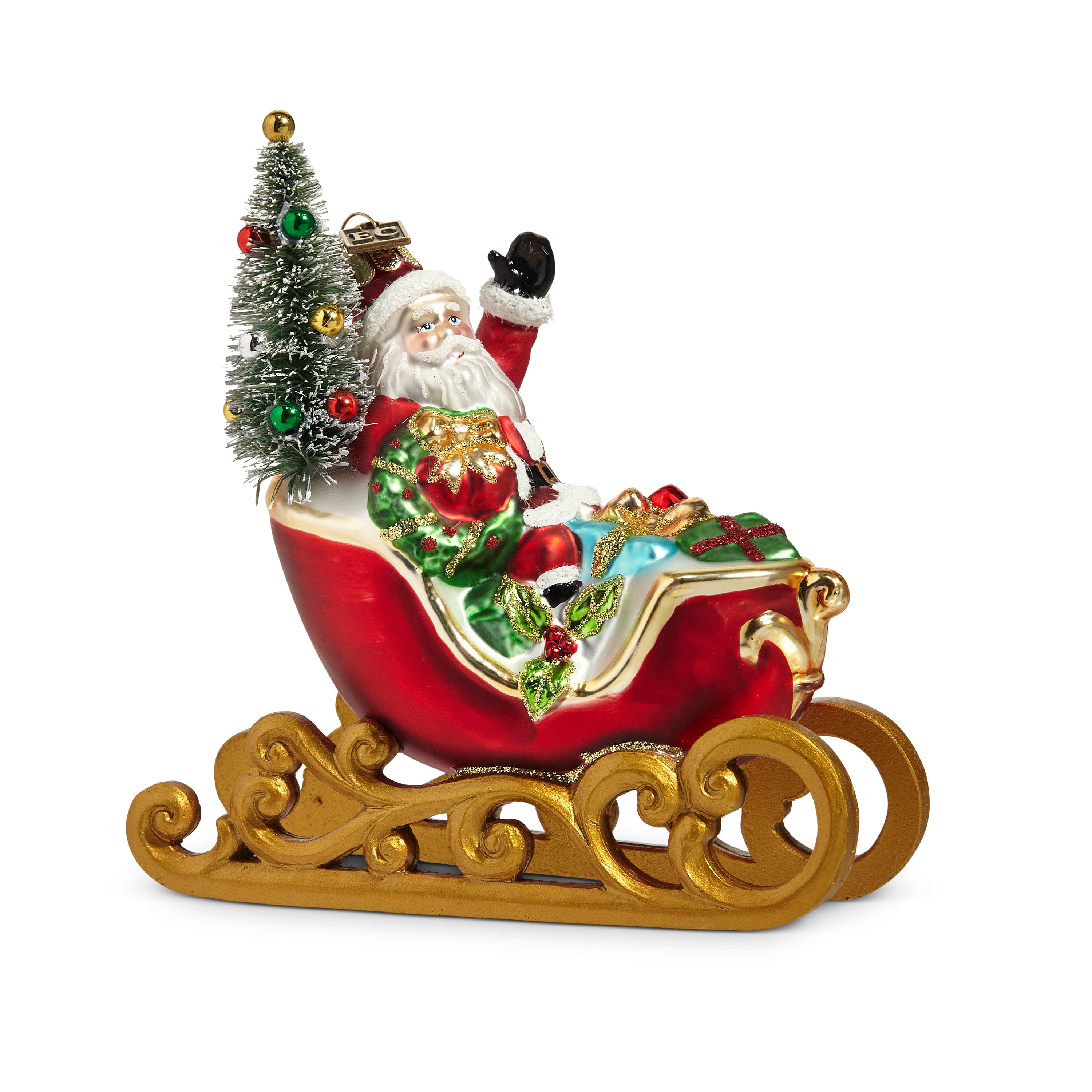 A multicolor glass collectible Christmas ornament depicting Santa Claus sitting in a sleigh, with a Christmas tree and gifts in the background.