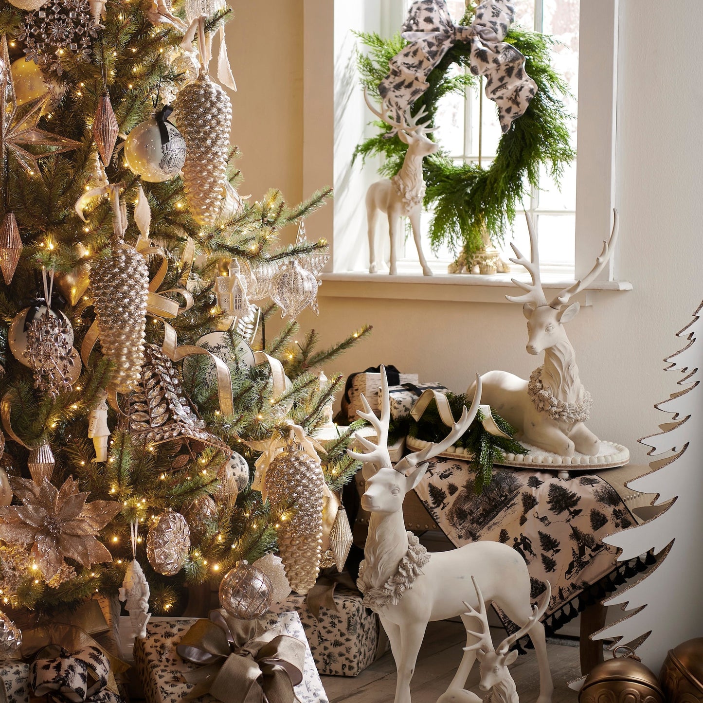 Decorative Christmas scene with a tree, ornaments, and deer figurines in a room.