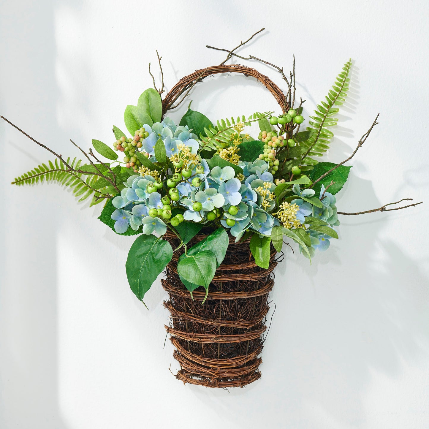 Decorative wall hanging with greenery and flowers on a white background