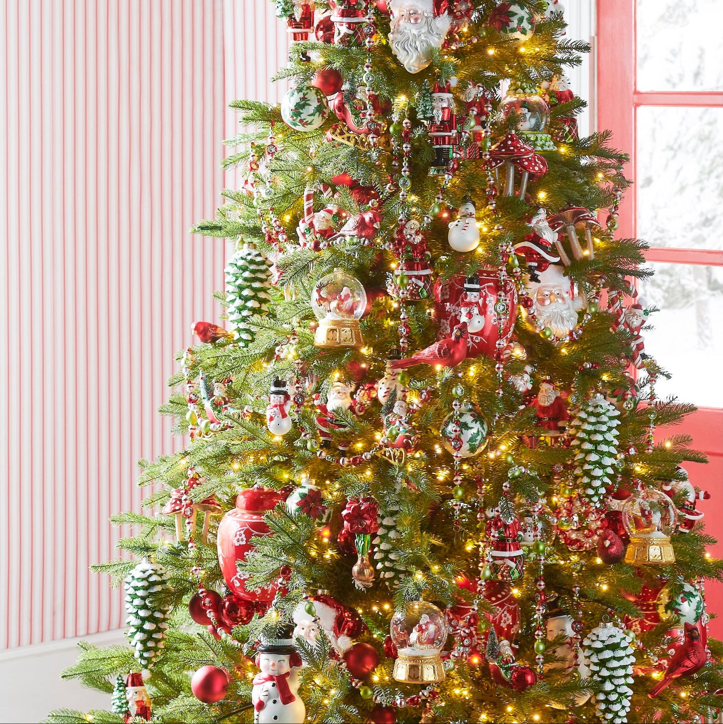 Decorated Christmas tree with lights and ornaments in a room with pink walls.