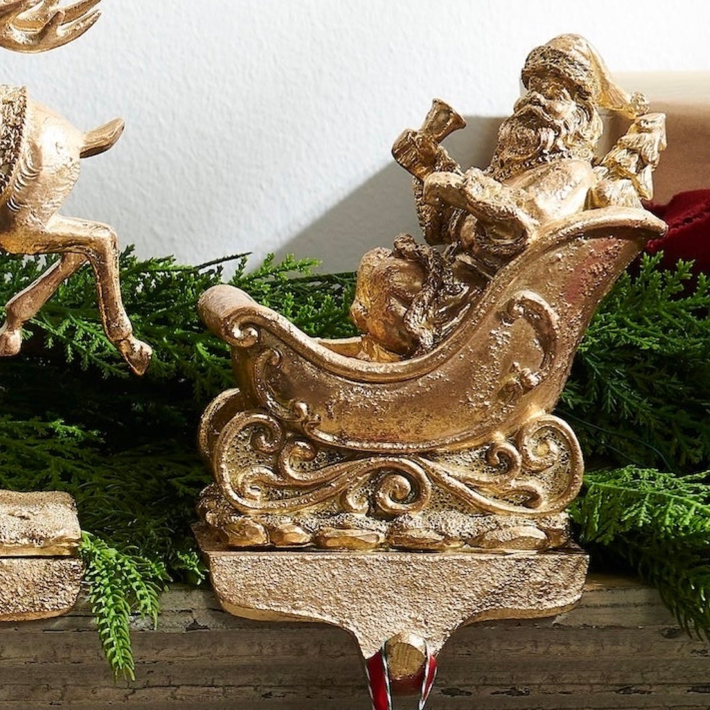 Decorative gold Santa Claus figure in a sleigh with greenery in the background