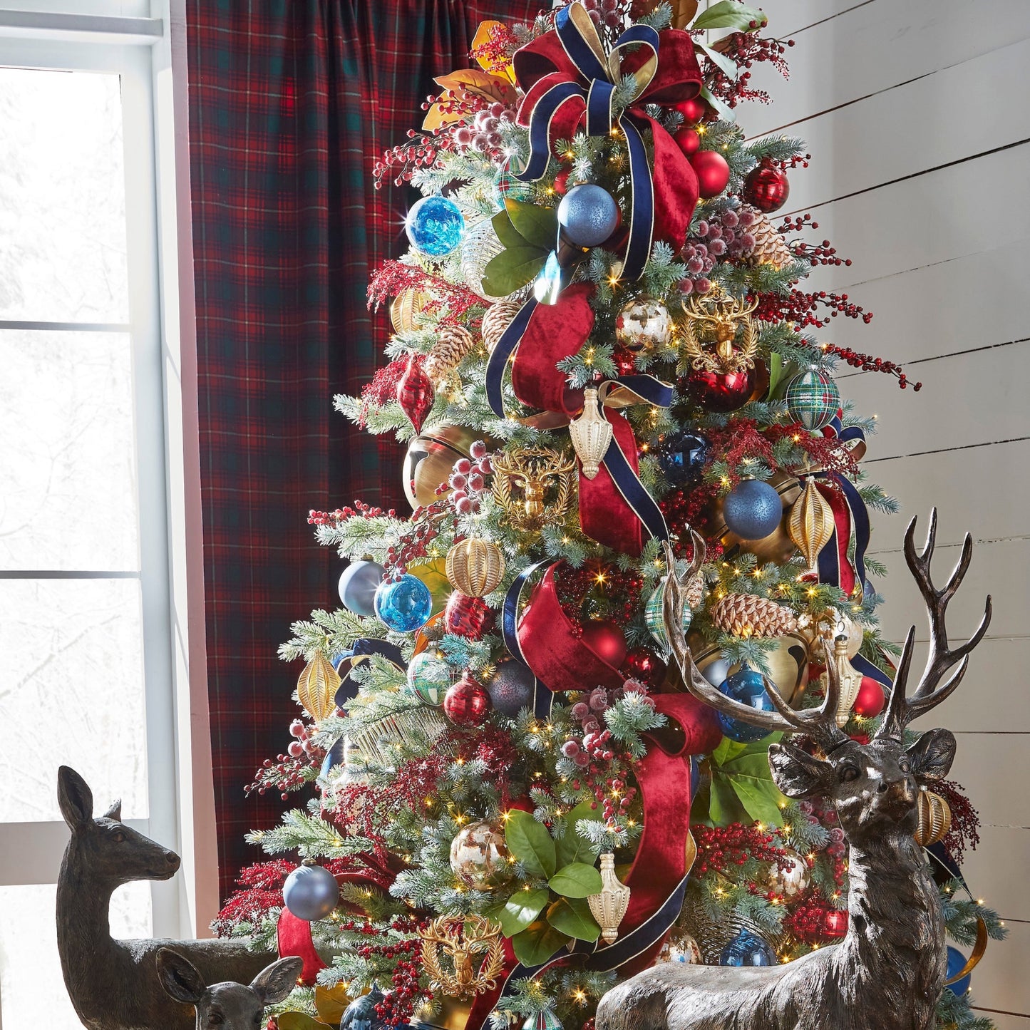 Decorated Christmas tree with ornaments and ribbons in a room with a window and plaid curtain.