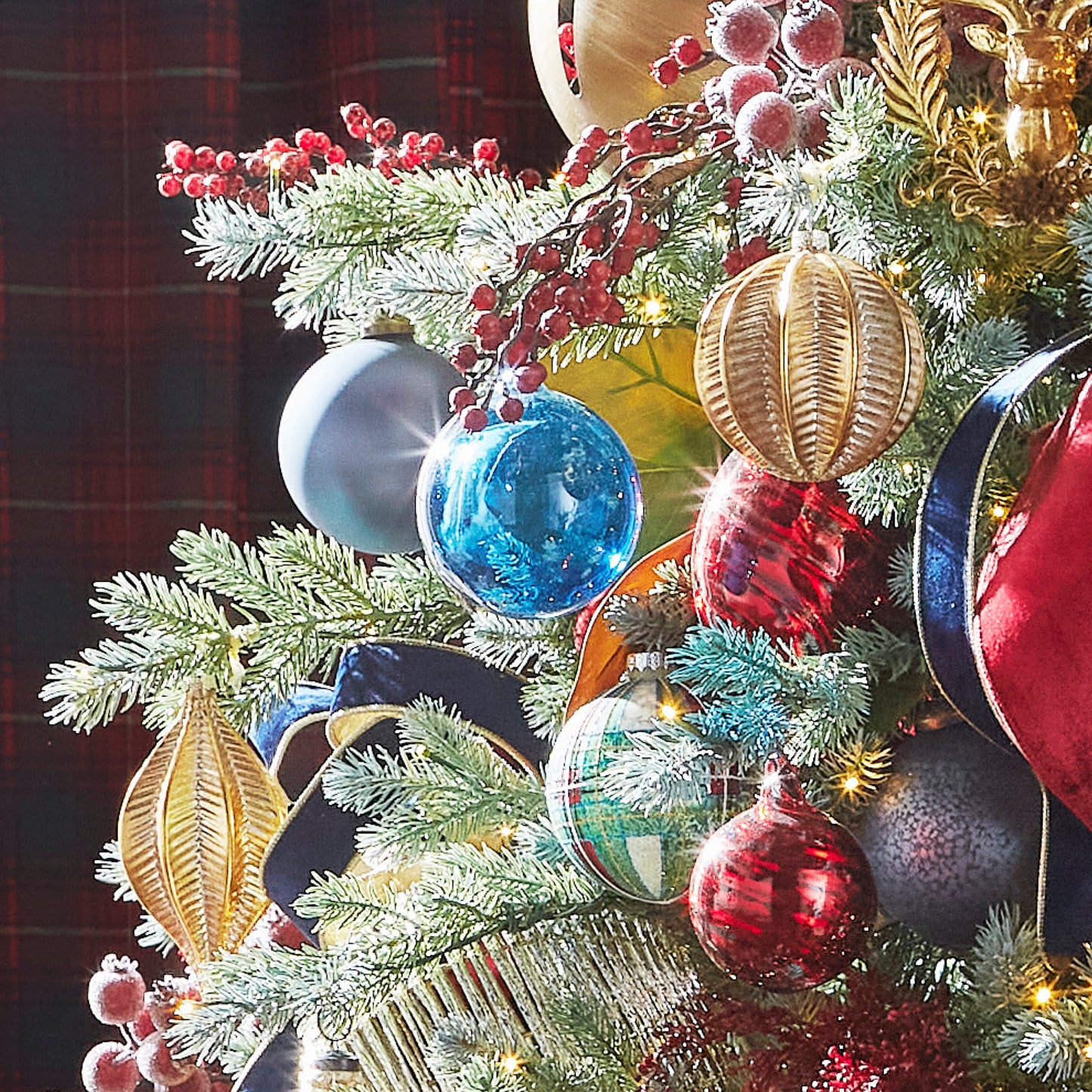 Decorative Christmas tree with colorful ornaments and red berries against a dark background