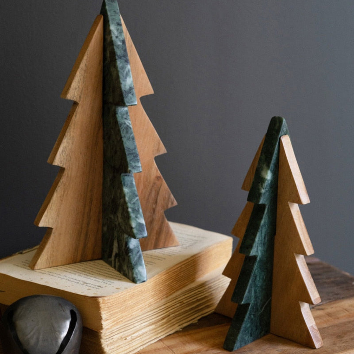 Two wooden tabletop Christmas trees decorated with green marble and acacia wood, displayed on a wooden table.