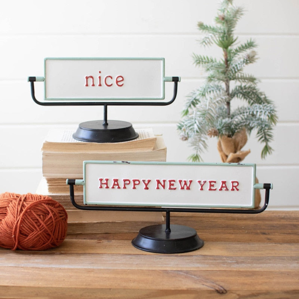Decorative sign with 'Happy New Year' text on a wooden surface with books and a small tree.