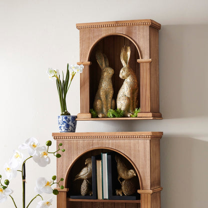 Wooden bookshelf with decorative items including books, figurines, and plants against a plain wall.