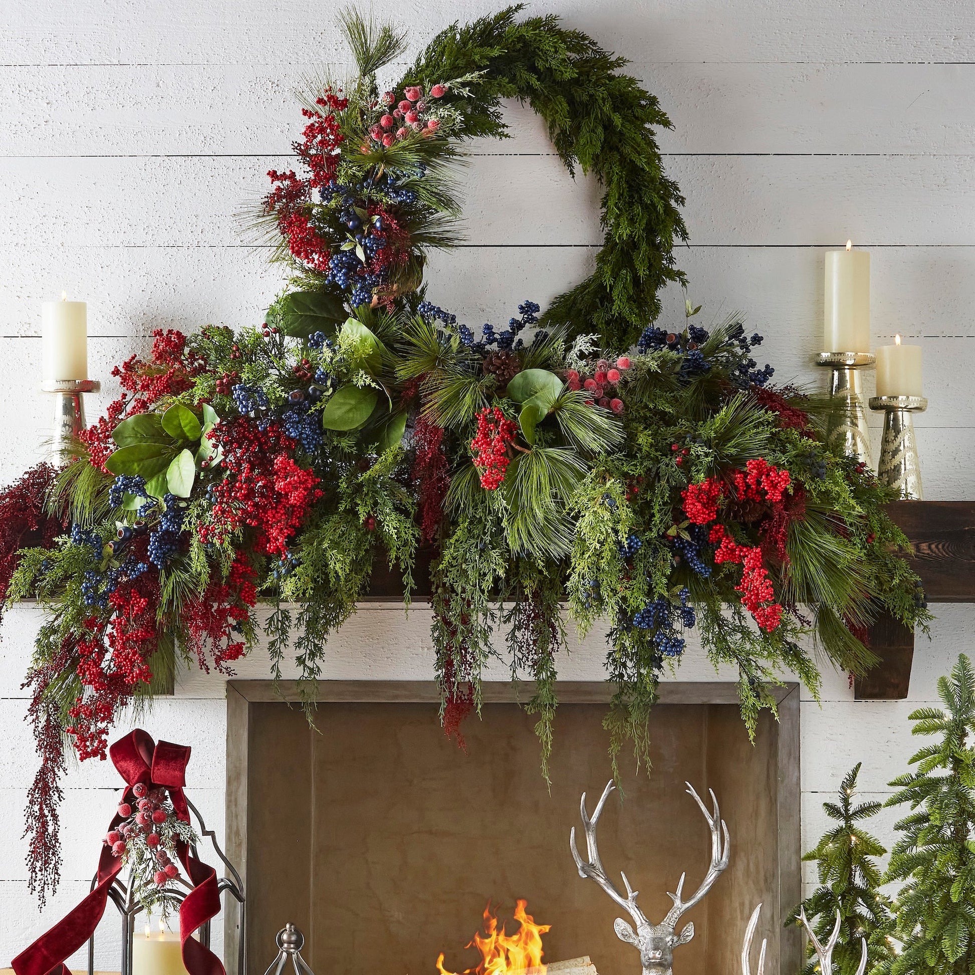 Decorative Christmas mantel with greenery, red berries, and candles in a cozy living room.