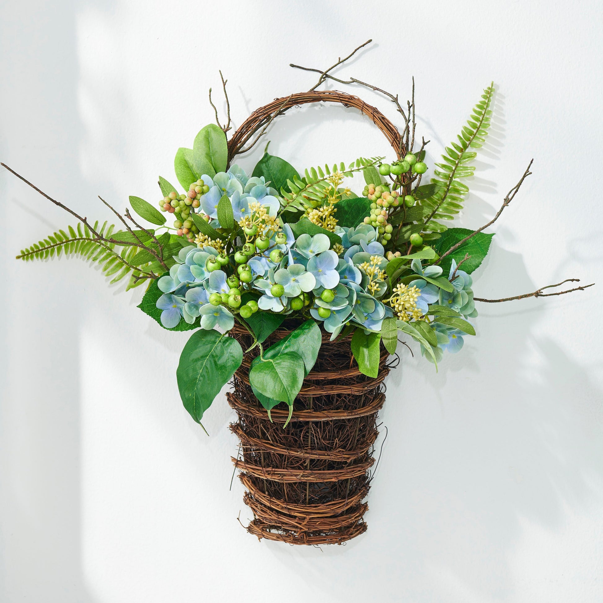 Decorative wall hanging with greenery and flowers on a white background