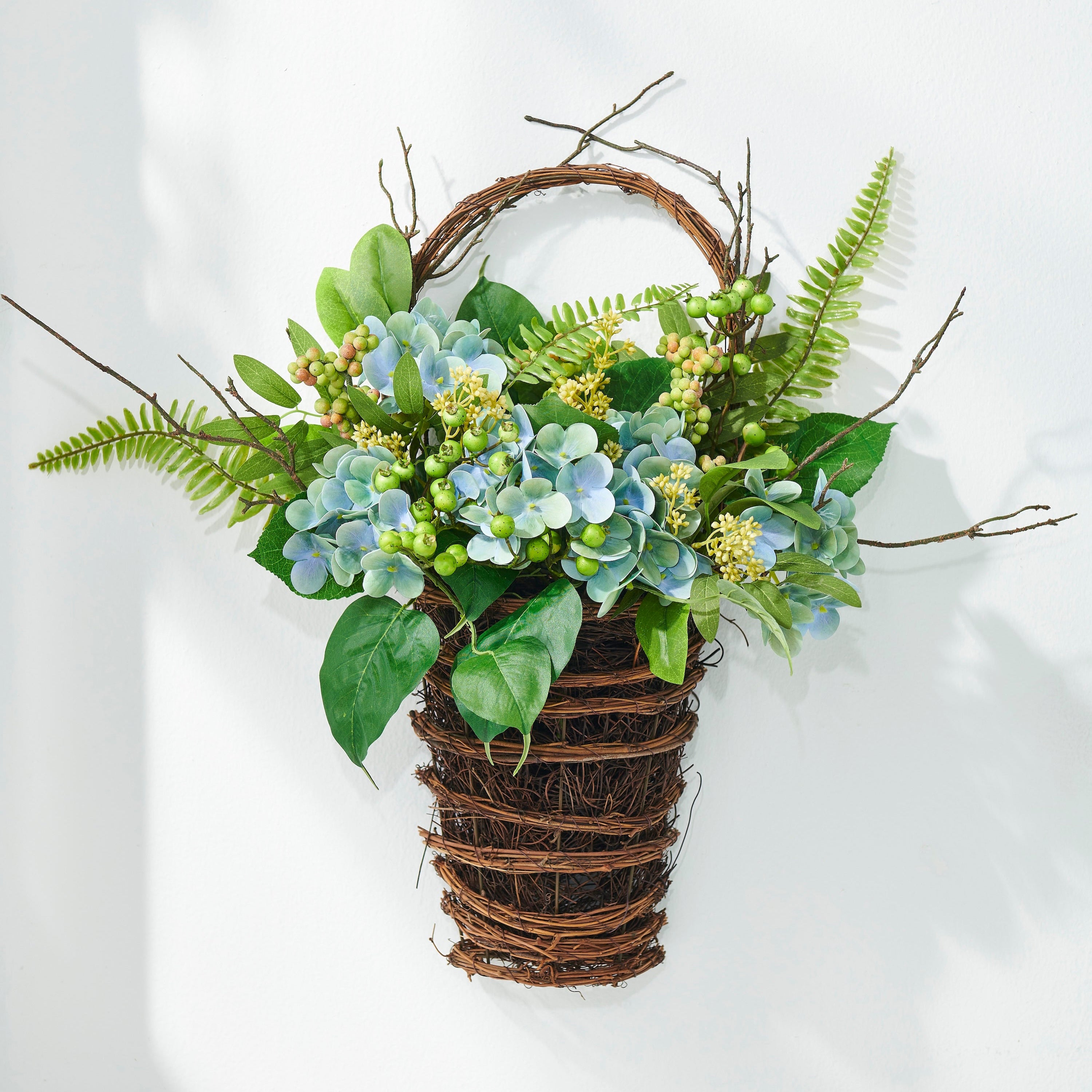 Decorative wall hanging with greenery and flowers on a white background