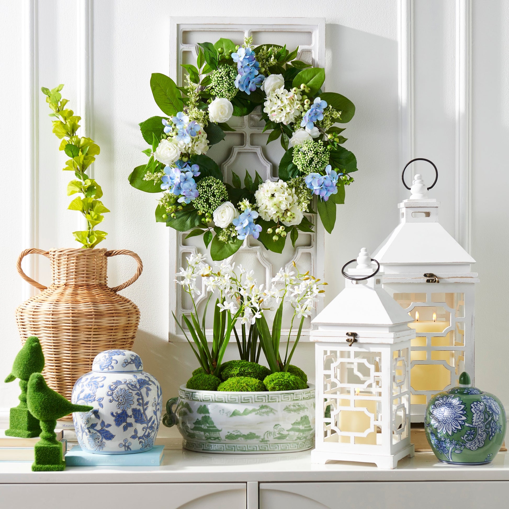 Decorative items including a floral wreath, lantern, and vases on a white surface.