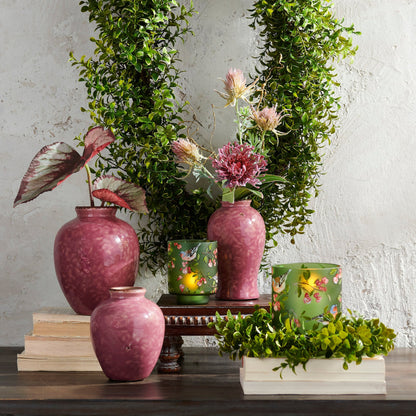 Decorative setup with pink vases, a mirror, and floral arrangements against a textured wall.