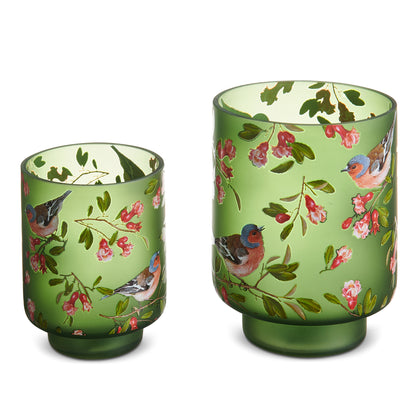Two green glass tumblers with floral and bird pattern on a white background