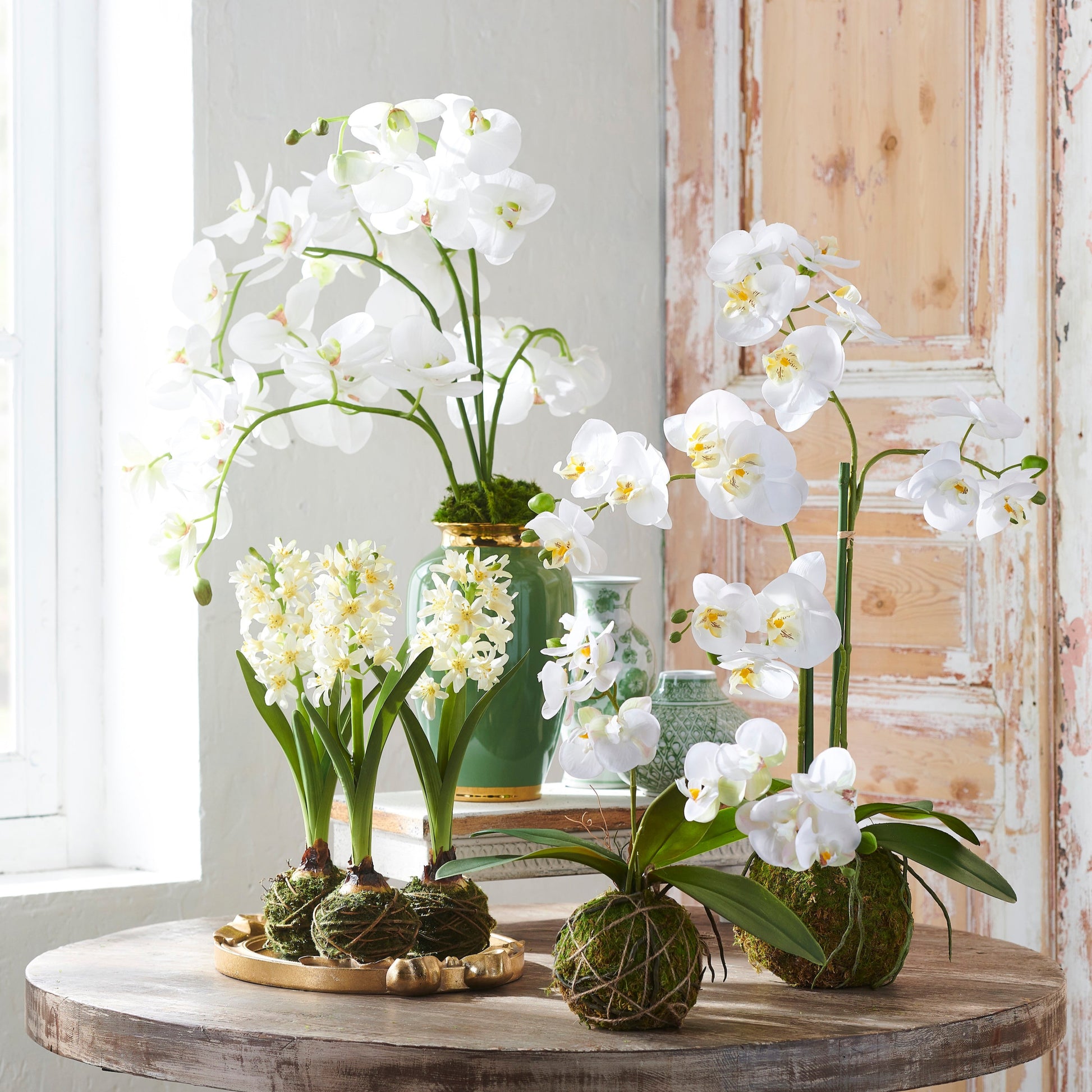 White orchids in decorative pots on a wooden table with a light background