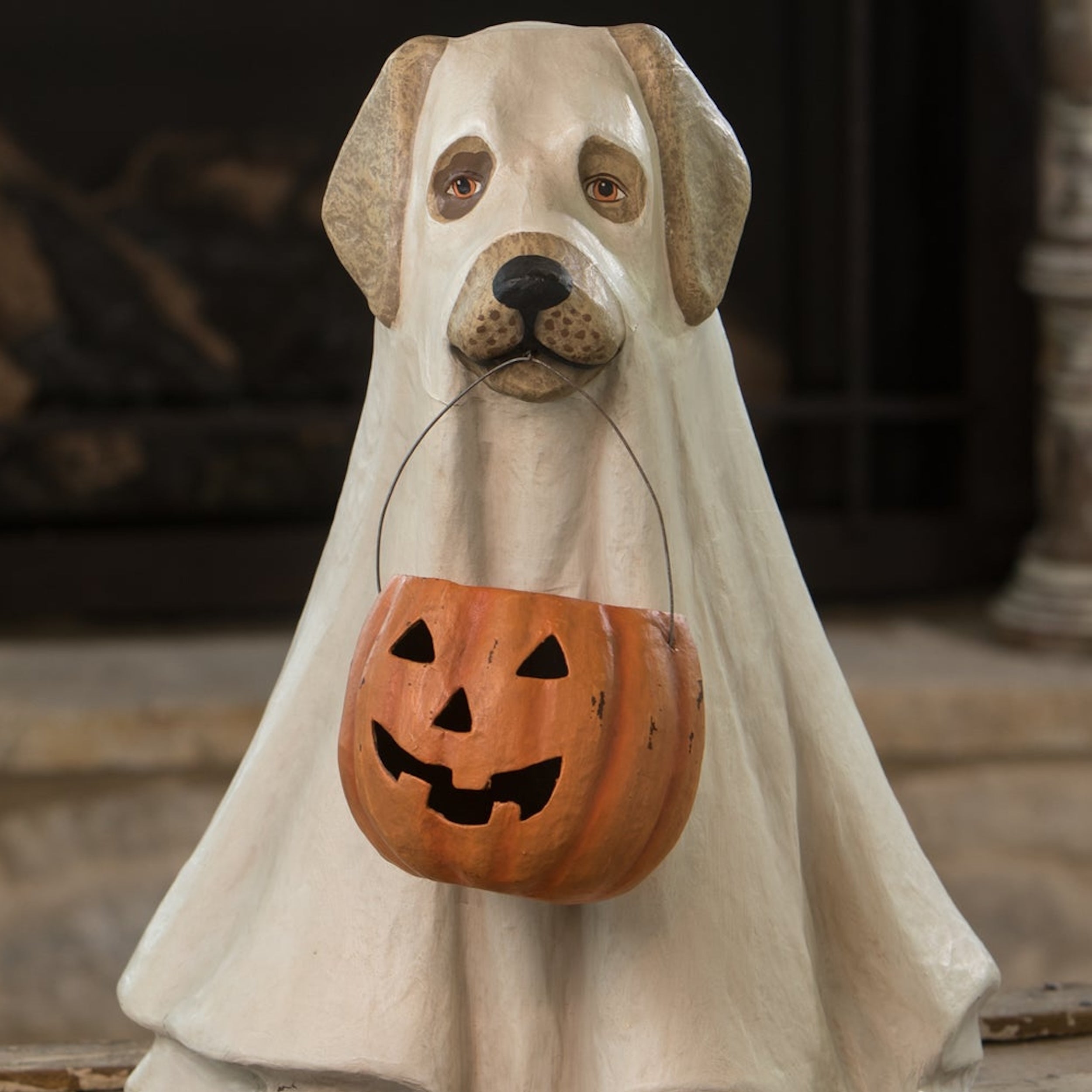 Dog-shaped Halloween decoration holding a carved pumpkin bucket.