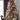 Decorated Christmas tree with red and blue ribbons, ornaments, and lights in a room setting.