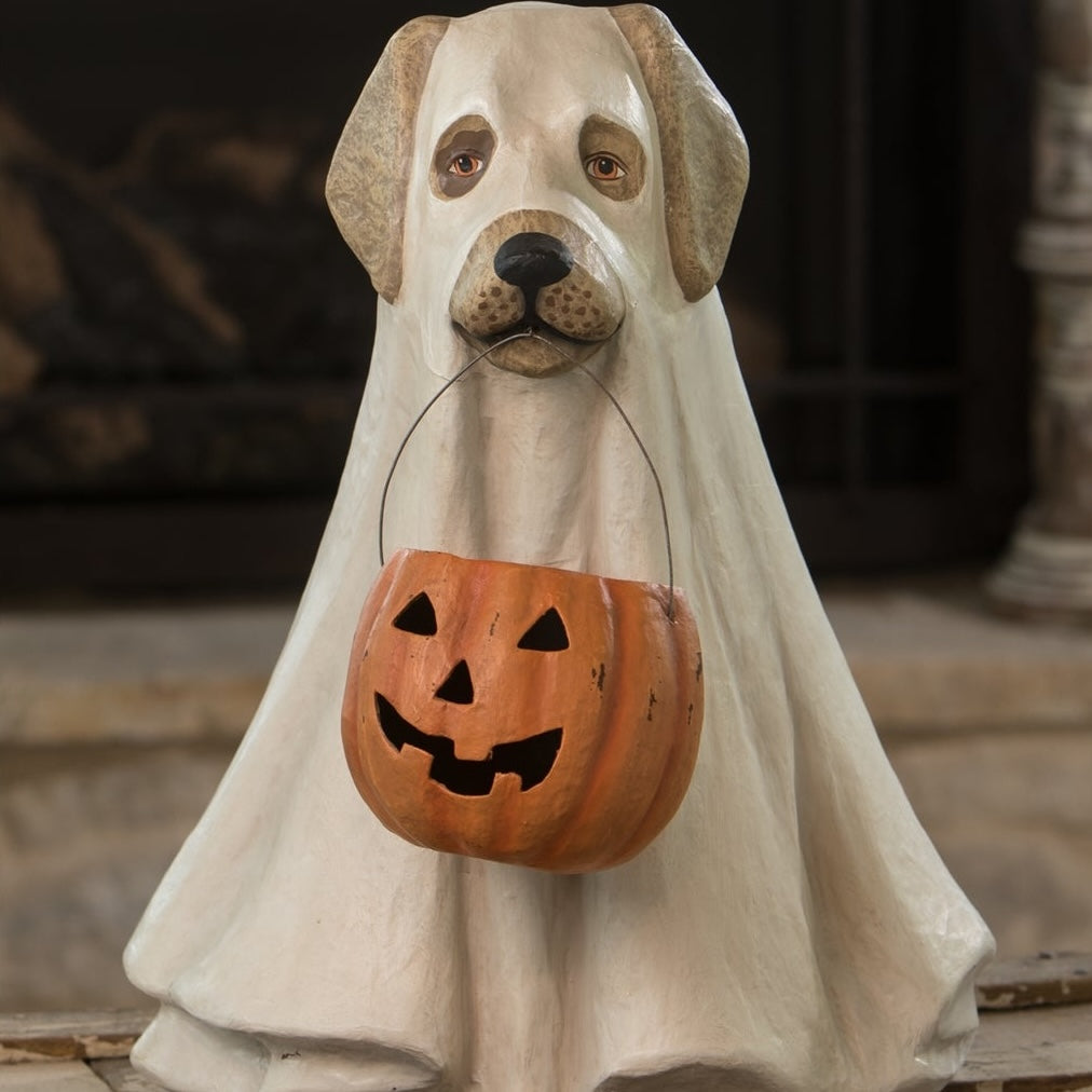 A paper mache statue of a ghost dog with a Halloween pumpkin candy bowl hanging from its mouth.